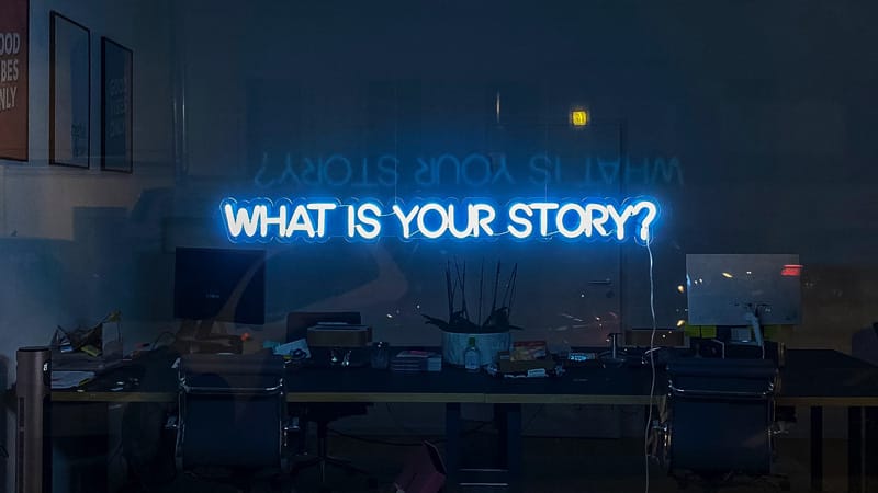 Foto con scritta a neon blu "What is your story?"